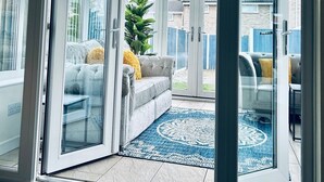 A modern living room with a glass door leading to a patio area. - Holiday Home with Parking , Near Colchester Zoo (Essex)