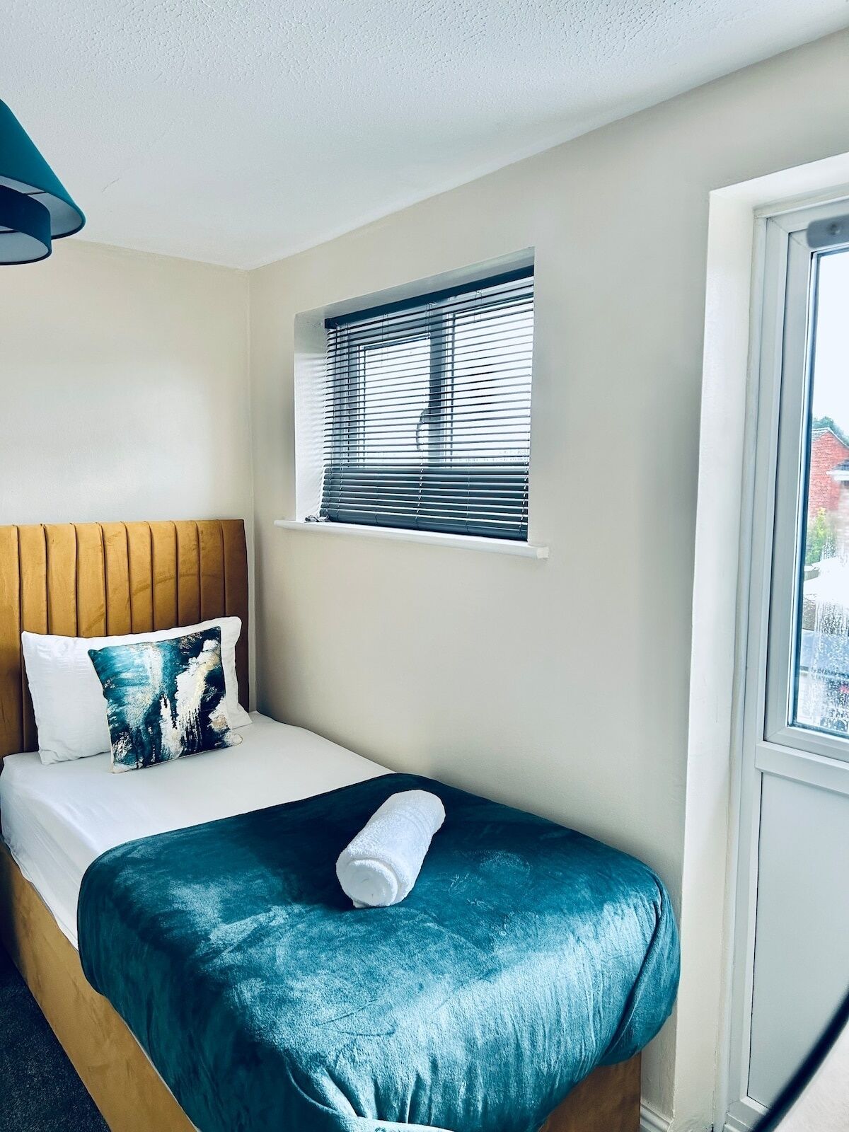 Una habitación de hotel con una cama, una ventana con persianas y una vista al exterior.
