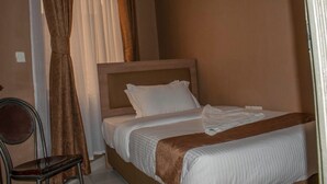 A hotel room with a bed, a chair, and curtains. - Katani Resort  (Mlolongo)