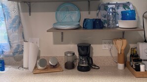 A kitchen with a countertop, a coffee maker, a jar, a plate, and a spoon holder. - Lovely 2-bedroom mobile home with AC in Okeechobee, on the canal near the locks. (Okeechobee)