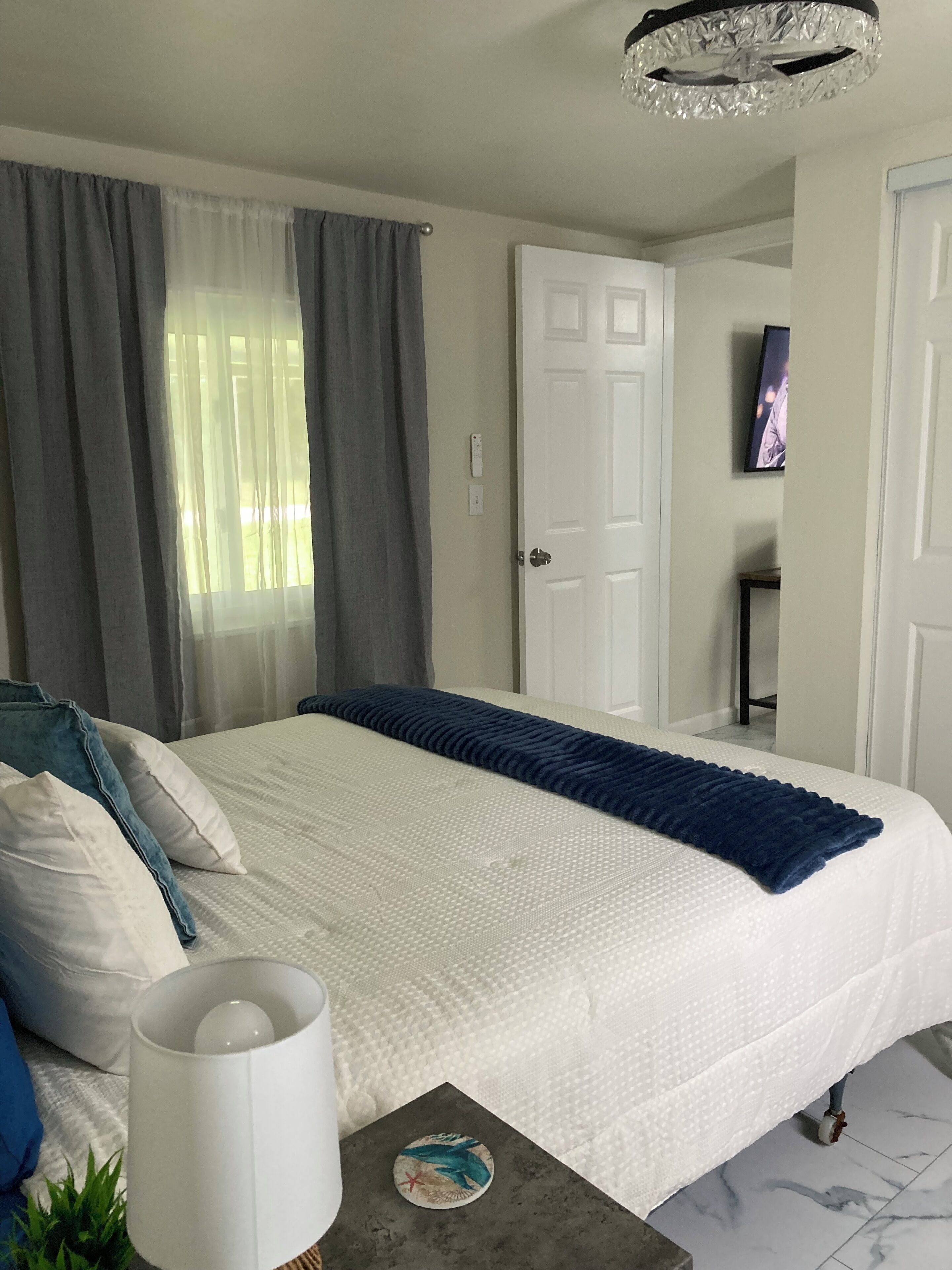Un dormitorio ordenado con cama, lámpara de noche y una mesita con un objeto decorativo.