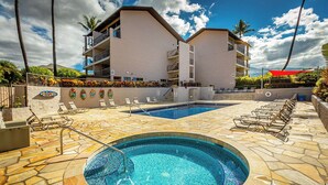 A hotel with a swimming pool, lounge chairs, and a building with balconies.