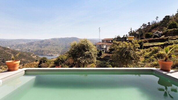 Ein Schwimmbad mit Blick auf eine hügelige Landschaft und Häuser.