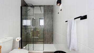 A modern bathroom with a glass-enclosed shower, a toilet, and a towel rack.