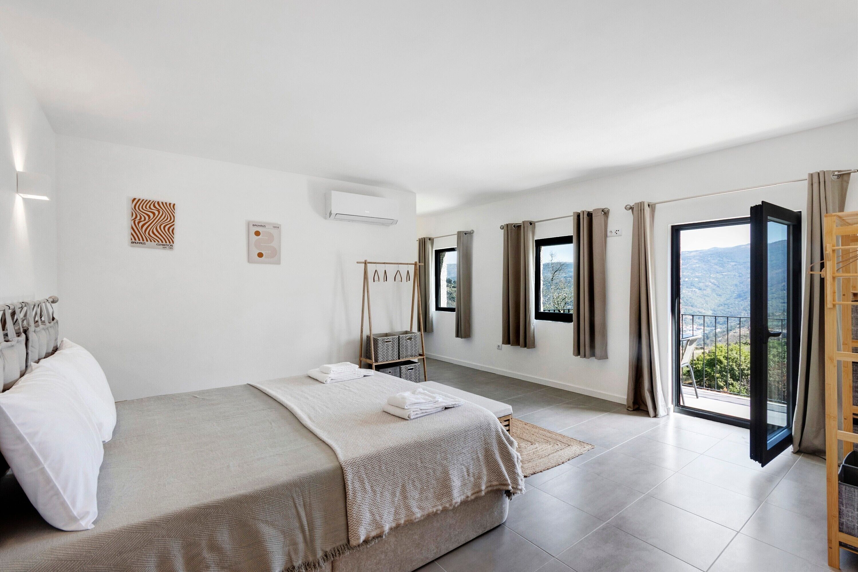 Un dormitorio con cama, armario, ventana y balcón.