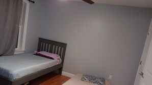 A small bedroom with a single bed, a window with curtains, and a door. - Walking distance Golf Course 4-bedroom house with Living  Dining and Family Room (Farmingdale)