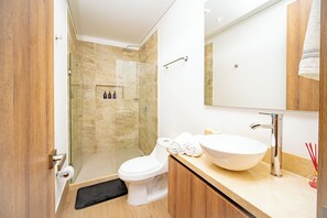 Une salle de bain moderne avec une douche à parois de verre, un lavabo blanc et un grand miroir.
