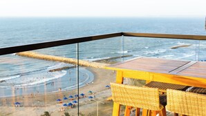 A balcony with a view of the beach and ocean.