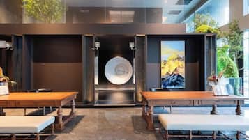 A modern interior with a central circular feature, wooden tables, benches, and potted plants.