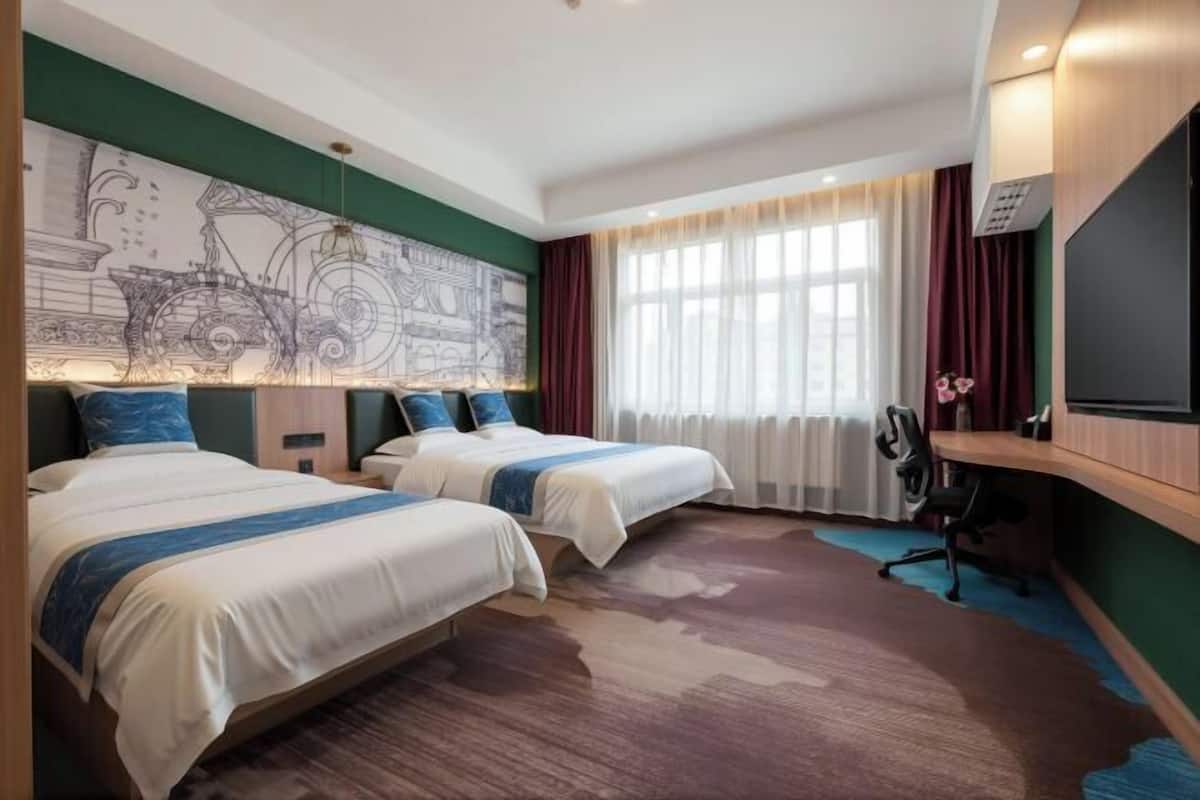 Une chambre d’hôtel avec deux lits, une grande fresque murale, un téléviseur à écran plat et un bureau avec une chaise.