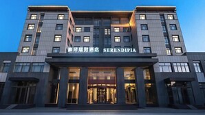 Un hôtel moderne doté d’une entrée imposante, de plusieurs étages et de fenêtres illuminées.