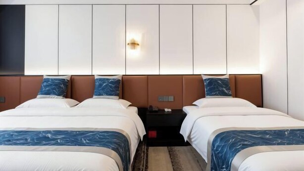 Een hotelkamer met twee bedden, een grote wandkast en een kleine tafel met een lamp.