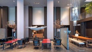 Un hall d’hôtel moderne comprenant un comptoir d’accueil, un espace salon et des éléments décoratifs.