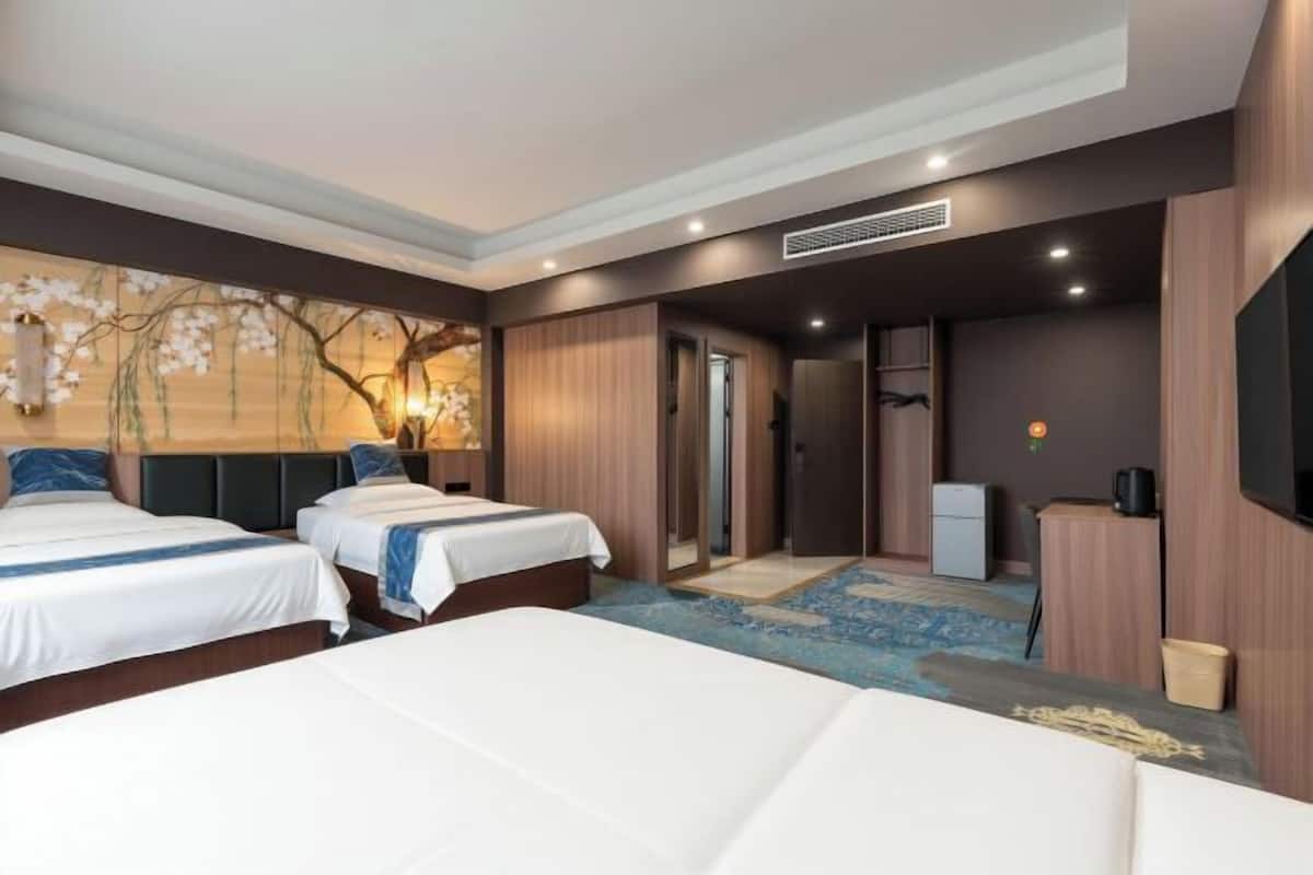 Une chambre d’hôtel avec deux lits, une télévision, un bureau et une petite kitchenette.