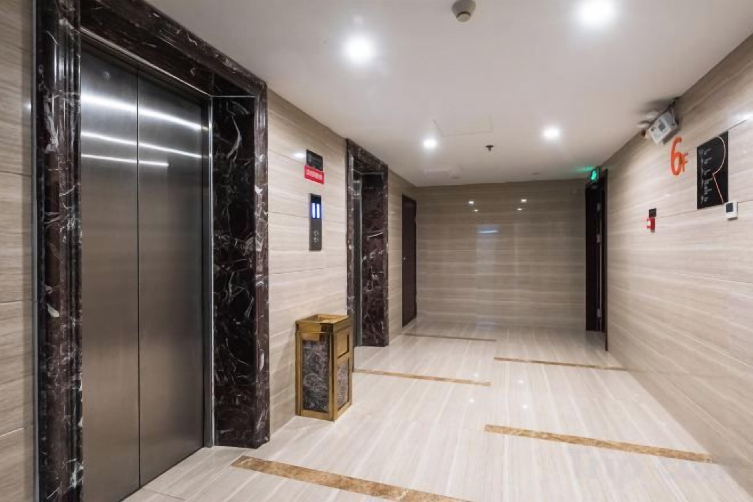 A modern elevator with a marble finish, a clean tiled floor, and a wall-mounted emergency phone.