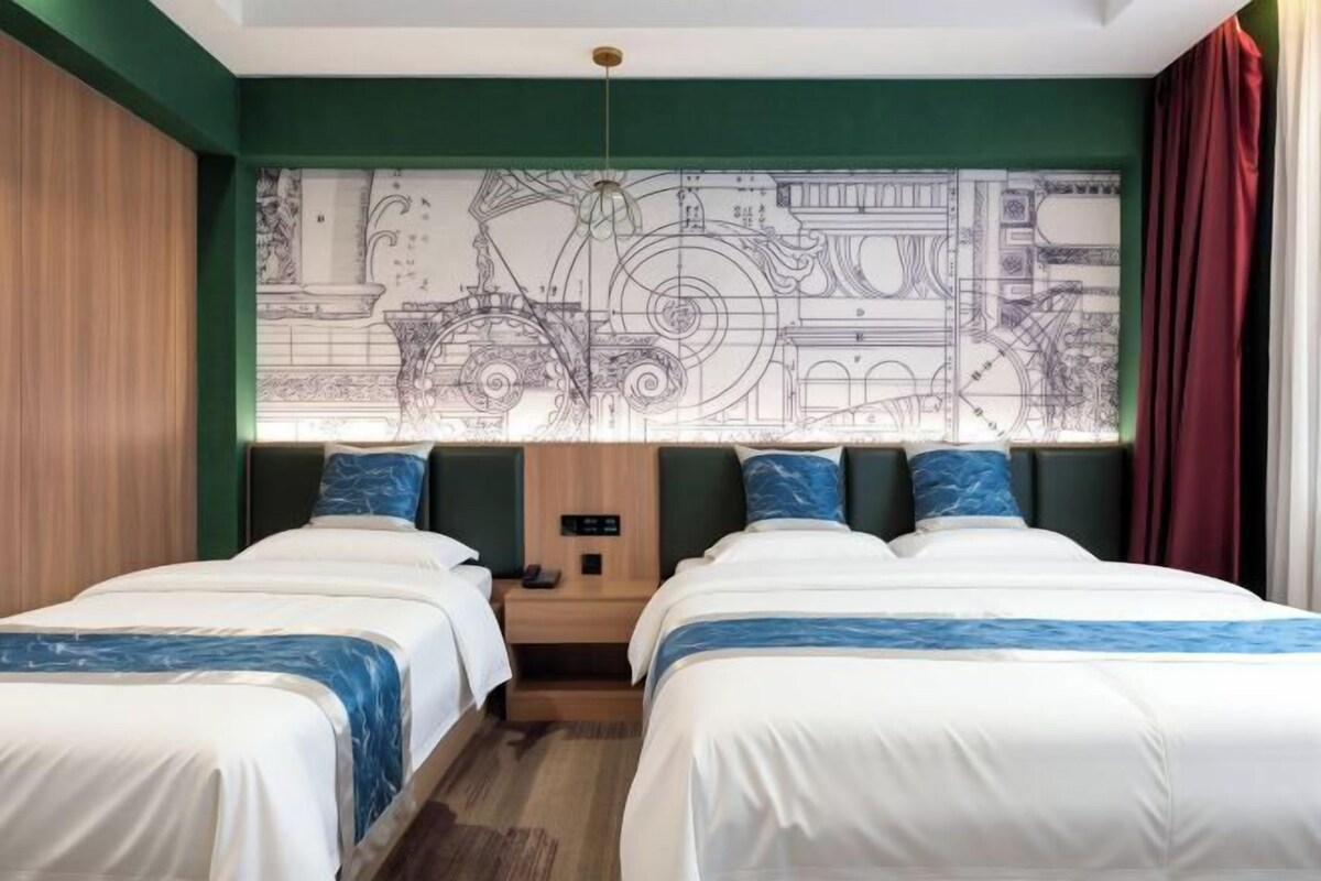 Habitación de hotel con dos camas, un ventanal con vista panorámica de la ciudad y una pared con diseño de plano.