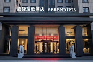 A hotel entrance with a large sign reading 'SERENDIPIA' and a welcoming entrance with steps and a statue.