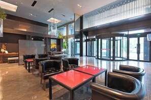 Un lobby moderno con mostrador de recepción, zona de estar y amplias ventanas.