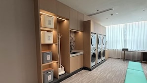 A laundry room with a washing machine, a sink, and a bench. - Phoenix Court Hotel (Jingzhou Ancient City Changjiang University) (Jingzhou)