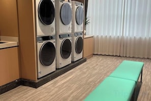 A laundry area with multiple washing machines and a bench. - Phoenix Court Hotel (Jingzhou Ancient City Changjiang University) (Jingzhou)