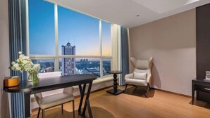A modern hotel room with a large window, a dining table, a chair, and a small side table. - Phoenix Court Hotel (Jingzhou Ancient City Changjiang University) (Jingzhou)