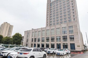A multi-story building with a parking lot in front. - Phoenix Court Hotel (Jingzhou Ancient City Changjiang University) (Jingzhou)
