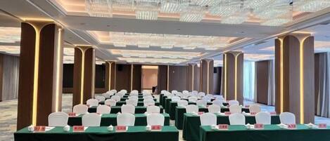 A conference room with rows of tables, chairs, and a chandelier.
