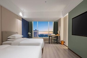 A hotel room with two beds, a desk, a chair, a TV, and a large window with a city view. - Phoenix Court Hotel (Jingzhou Ancient City Changjiang University) (Jingzhou)