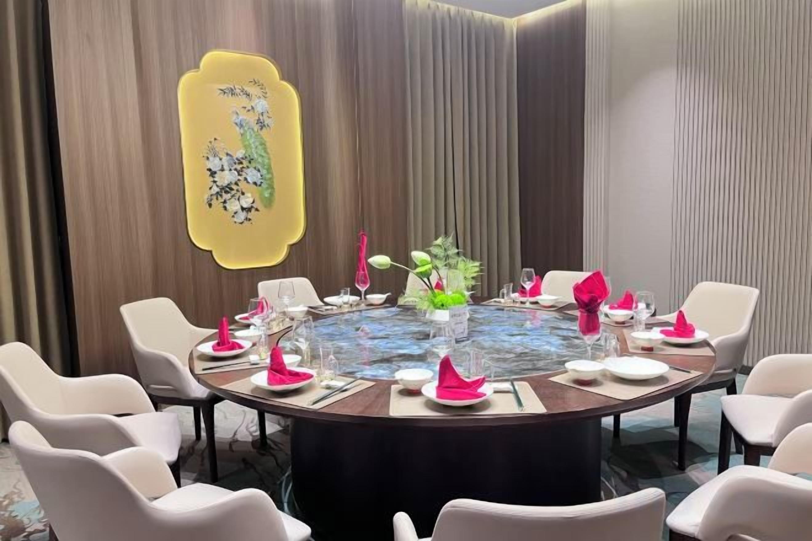 A round dining table with chairs, a floral centerpiece, and a yellow abstract artwork on the wall.