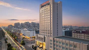 A high-rise hotel with multiple floors, a prominent sign at the top, and a view of the cityscape in the background.