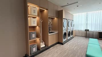A laundry room with a washing machine, a sink, and storage shelves.