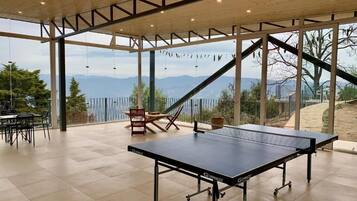An indoor ping pong table with a view of mountains through large windows.