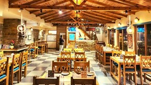 Un restaurante con mesas y sillas de madera, piso de tablones y pared de piedra.