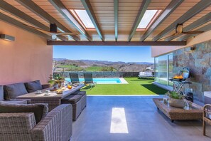 An outdoor patio with a pool, wicker furniture, and a view of the mountains.