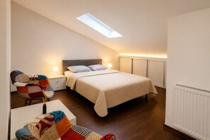 A bedroom with a bed, a desk, a chair, a skylight, and a radiator.