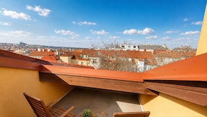 A rooftop terrace with a table and chairs, a potted plant, and a view of the cityscape. - Loft Jecna 43 Prague (Prague)