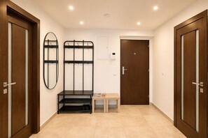 A hallway with wooden doors, a bench, a coat rack, and a small table with magazines.