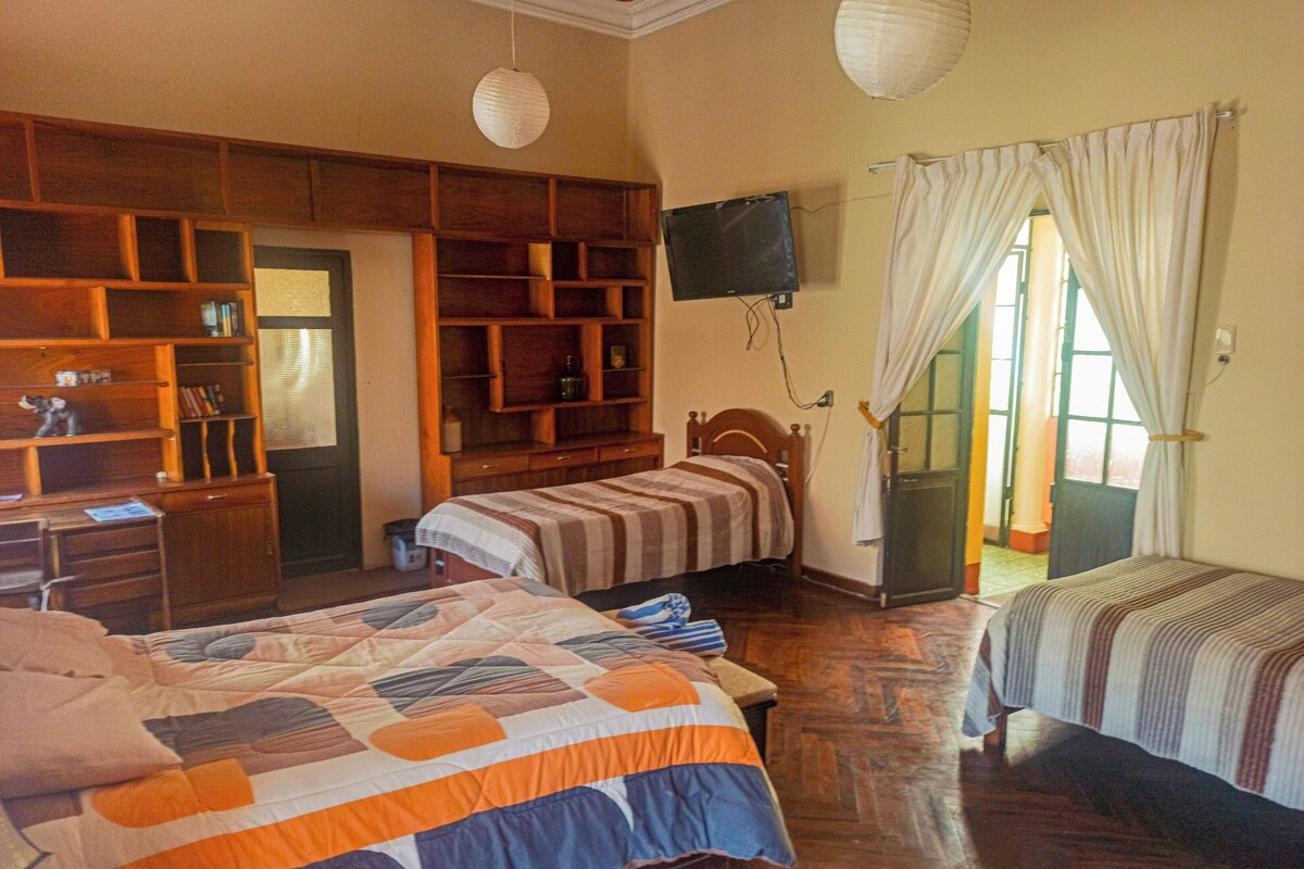 A bedroom with two beds, wooden furniture, a TV, and a window with curtains.