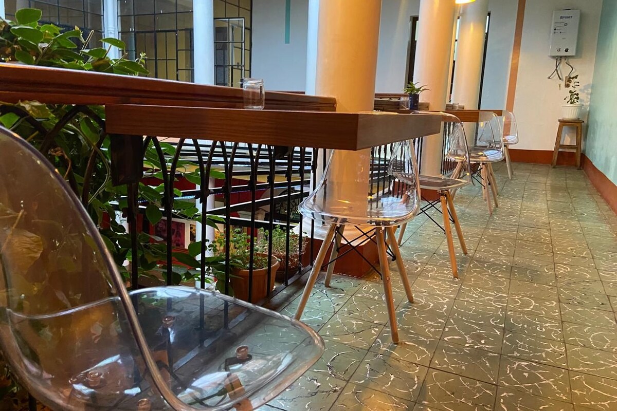 A spacious indoor area with clear glass chairs and tables, a tiled floor, and potted plants.