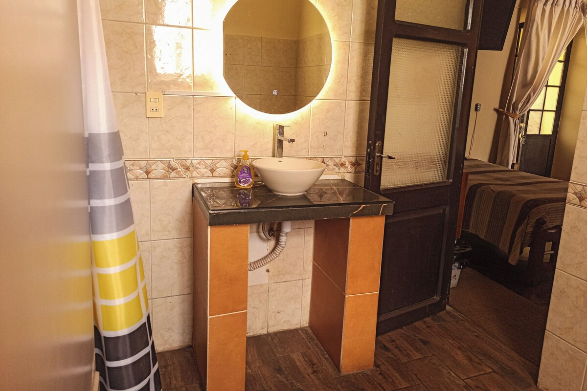 Baño con lavamanos, espejo y cortina de ducha.