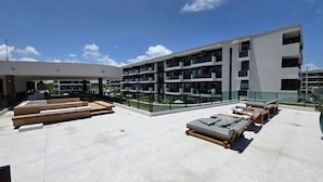 A rooftop terrace with outdoor seating, a pool, and a modern building with balconies. - Makia Beach Exp. Muro Alto 306B byLP (Ipojuca)