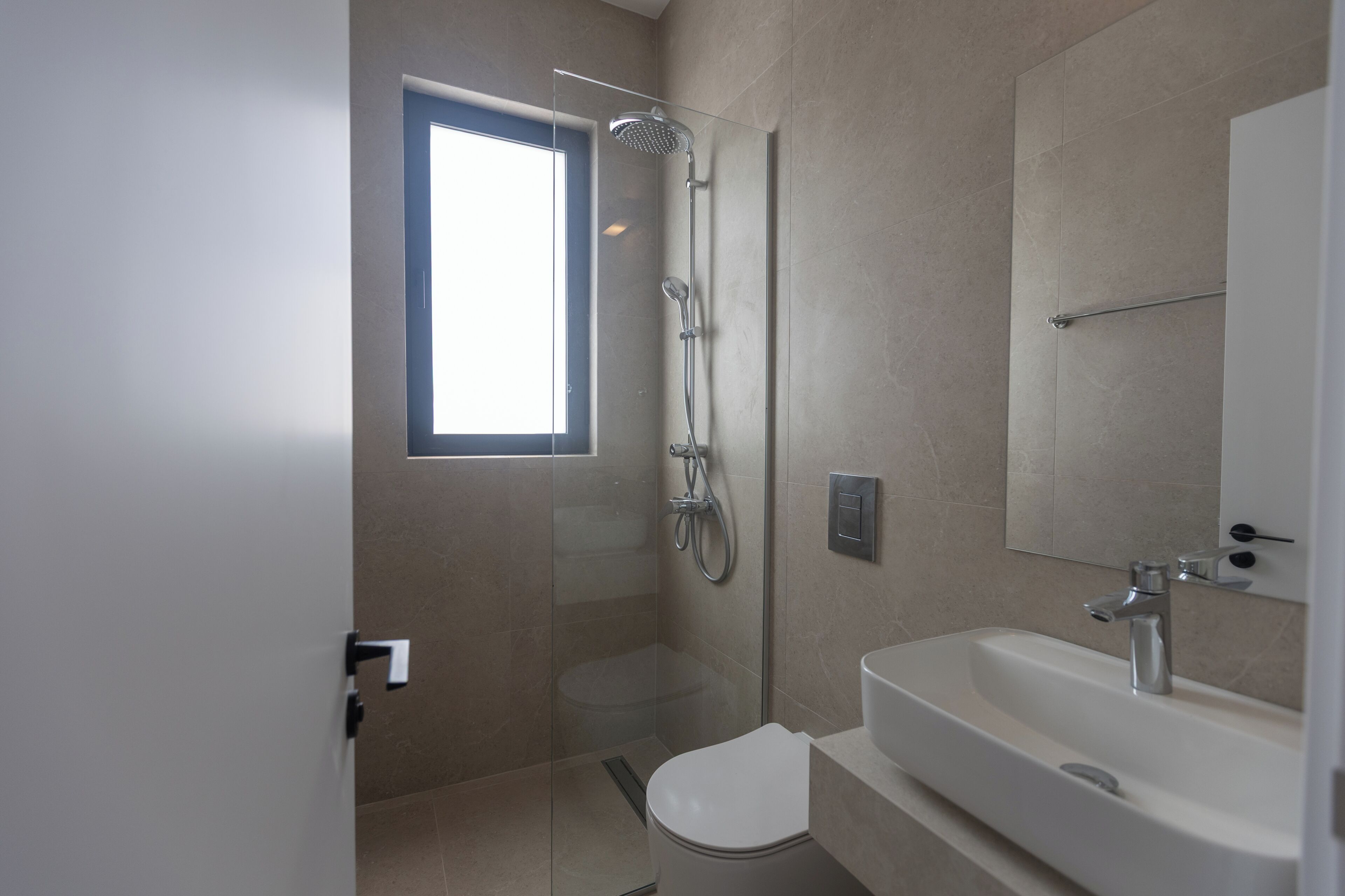 Une salle de bain moderne avec une douche à parois de verre, des toilettes et un lavabo avec un miroir au-dessus.