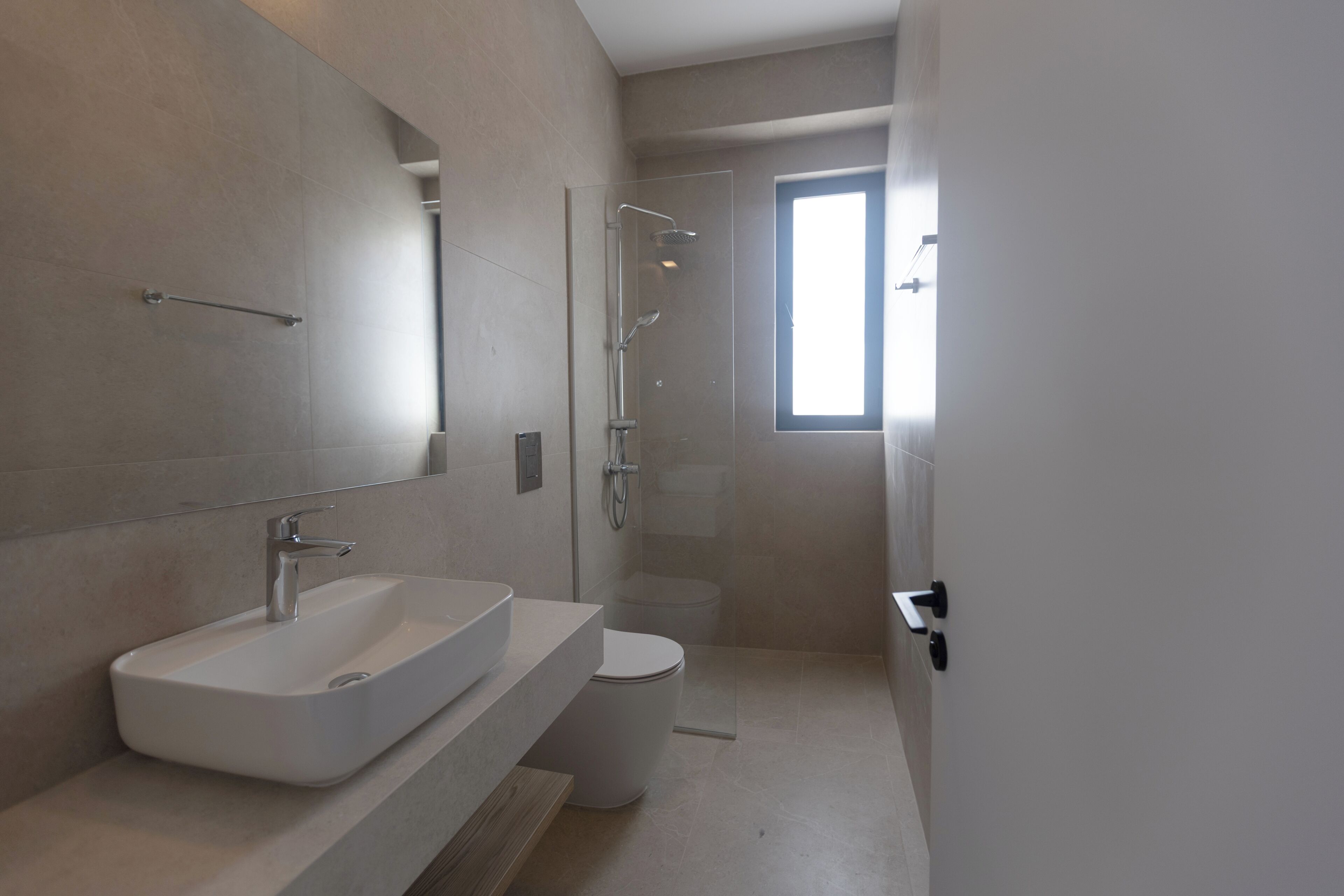 Een moderne badkamer met een groot wastafel, toilet en douchecabine.