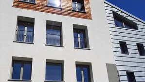 Un immeuble à plusieurs étages dont la façade est composée d’éléments en bois et en métal, avec de nombreuses fenêtres et une porte d’entrée bien visible.