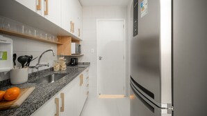 A modern kitchen with white cabinets, a granite countertop, a stainless steel refrigerator, and a sink. - Leblon | 5min to Beach & Perfect Location (Rio de Janeiro)