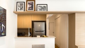 A modern kitchen with a built-in refrigerator, wooden cabinets, and a dining area with a round table and chairs.