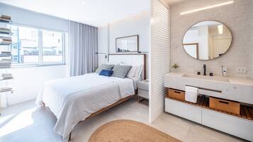 Een moderne slaapkamer met een bed, nachtkastje en een groot raam.