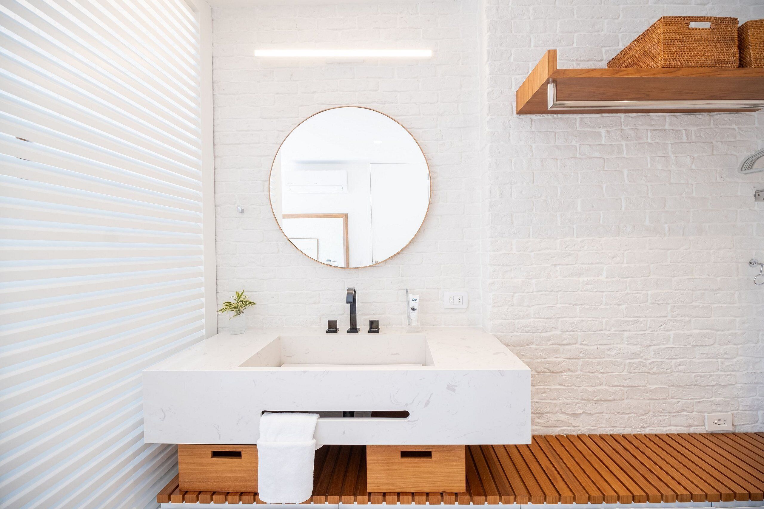 Une salle de bain moderne avec un lavabo blanc, un miroir rond et un meuble-lavabo en bois.