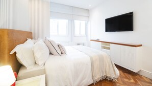A bedroom with a bed, a TV mounted on the wall, and a window. - Impeccable apartment in a great location in Leblon (Rio de Janeiro)