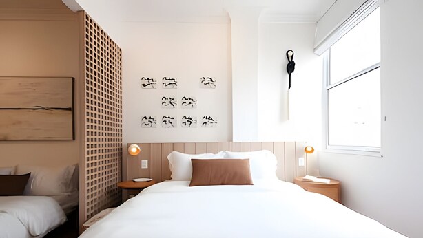 Una habitación de hotel moderna con una cama grande, dos mesitas de noche, un equipo de aire acondicionado de pared y un ventanal con vistas.